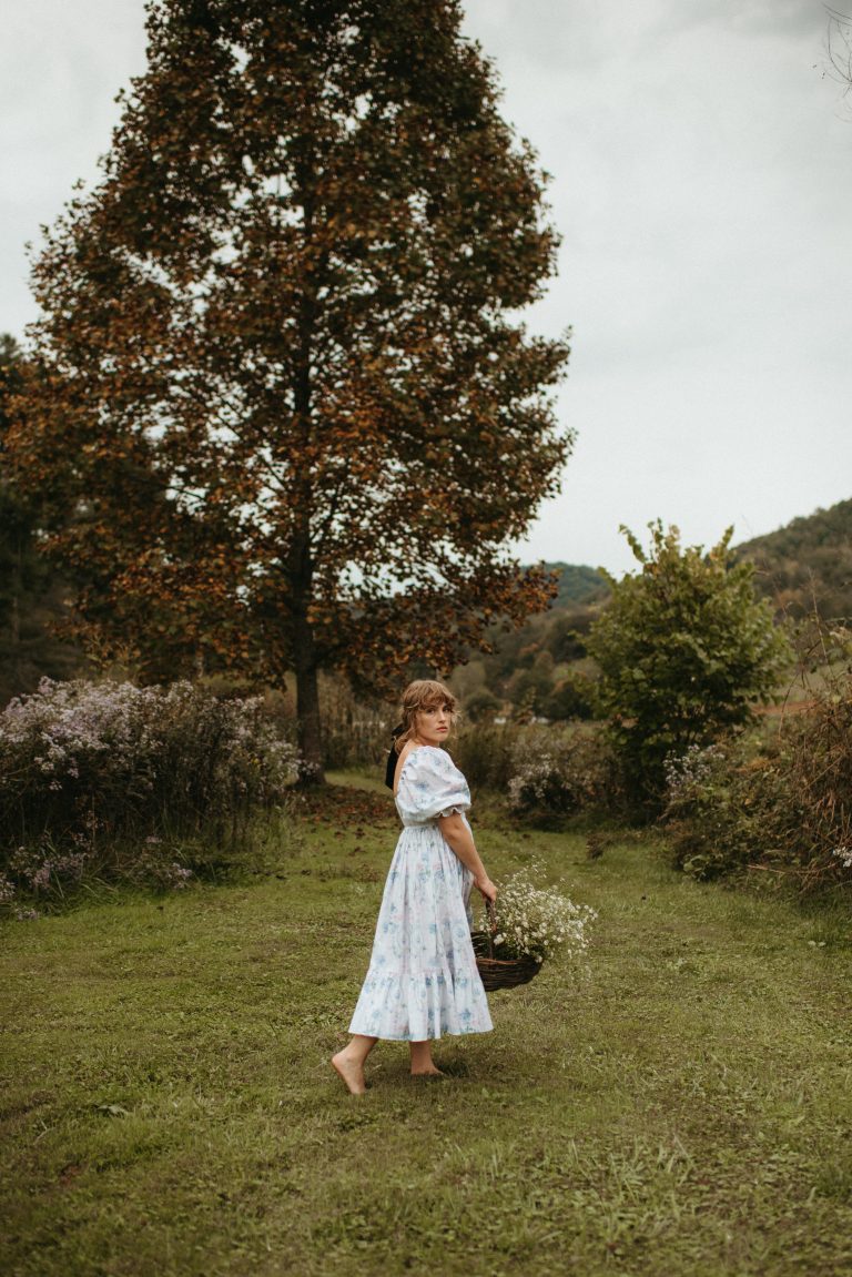 Woman in Selkie La Belle Etoile French Puff Dress running in field next to cottagecore barn