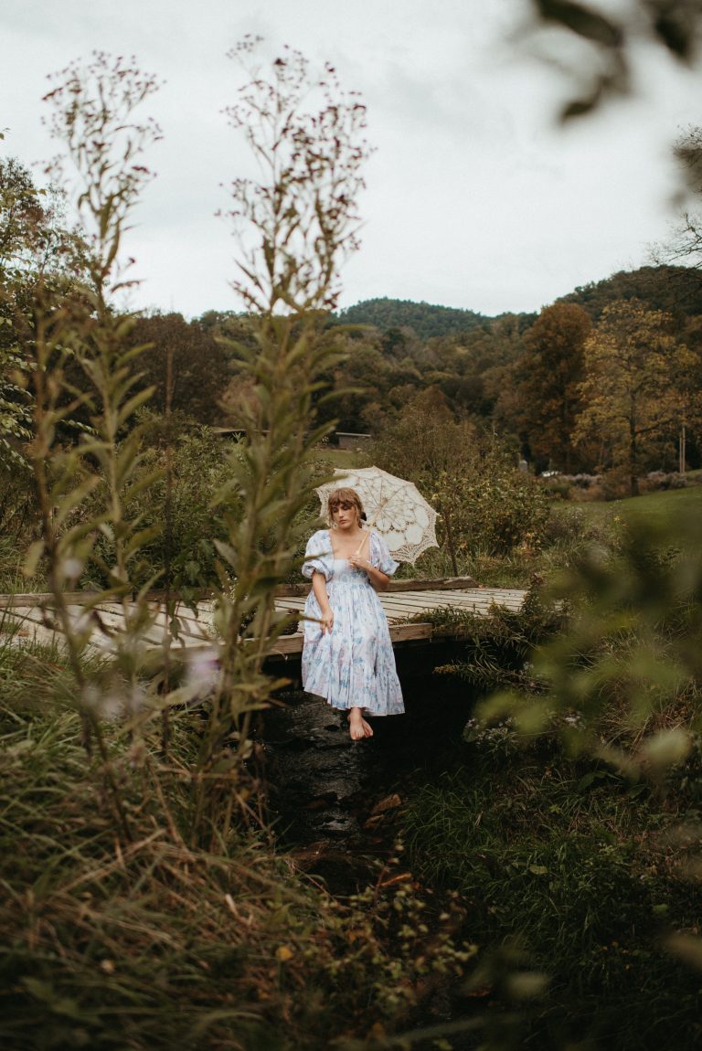 Woman in Selkie La Belle Etoile French Puff Dress running in field next to cottagecore barn