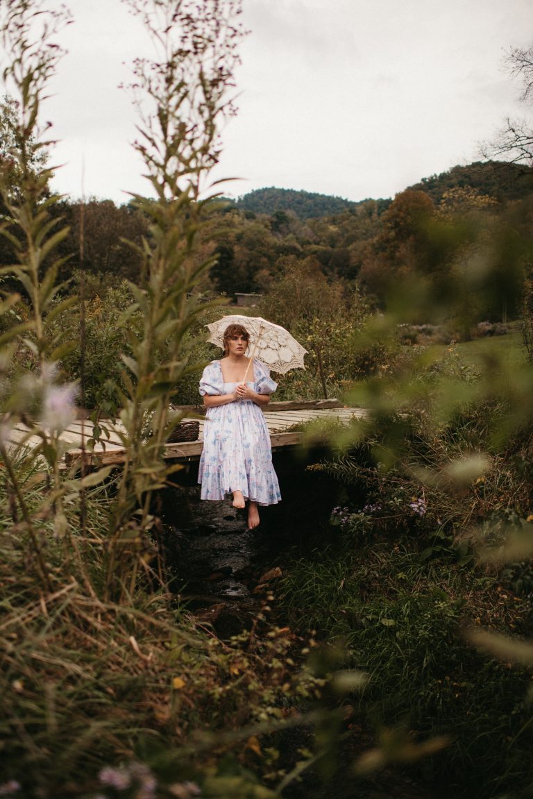 Woman in Selkie La Belle Etoile French Puff Dress running in field next to cottagecore barn