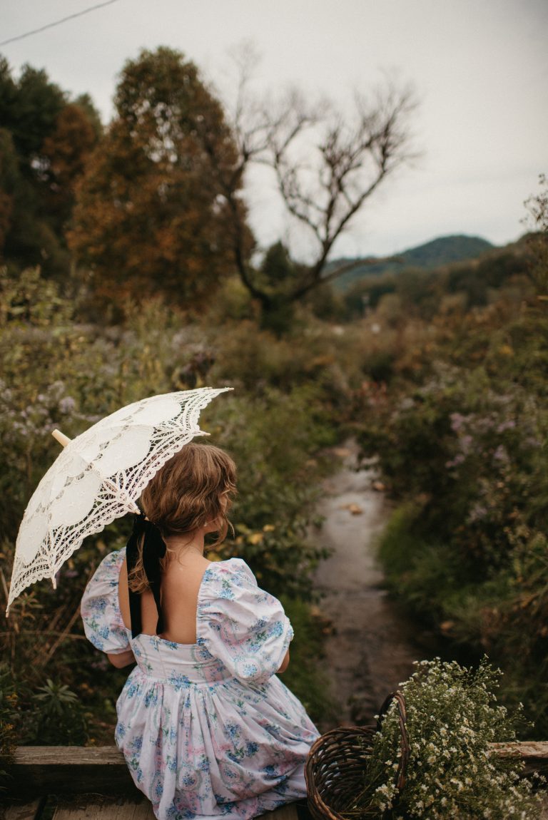 Woman in Selkie La Belle Etoile French Puff Dress running in field next to cottagecore barn