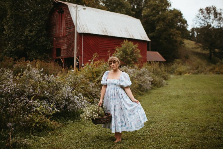 Woman in Selkie La Belle Etoile French Puff Dress running in field next to cottagecore barn