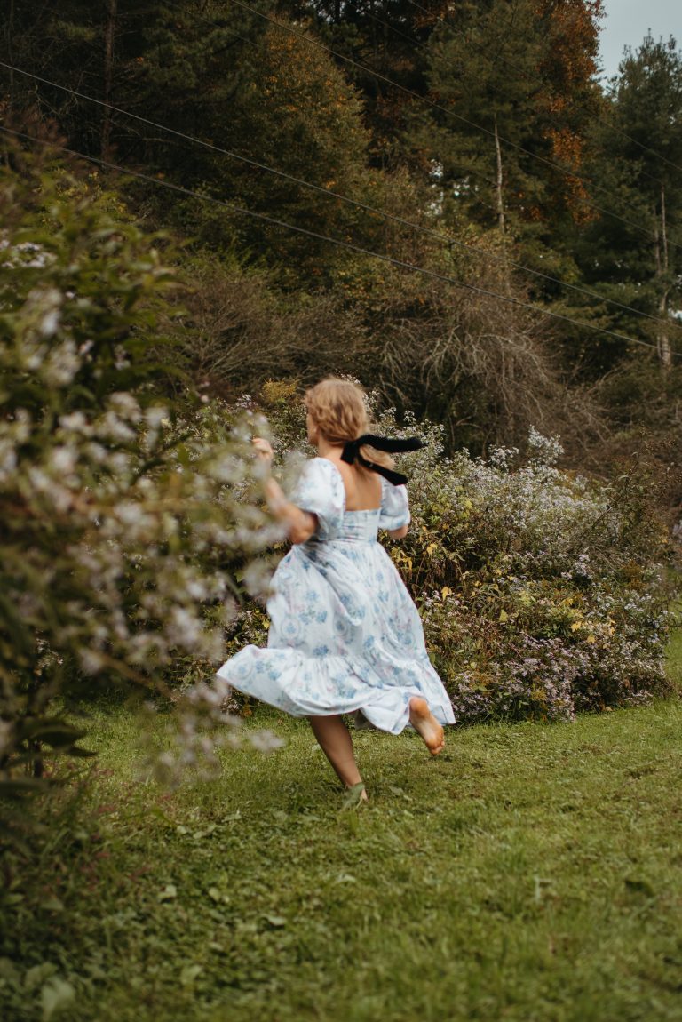 Woman in Selkie La Belle Etoile French Puff Dress running in field next to cottagecore barn