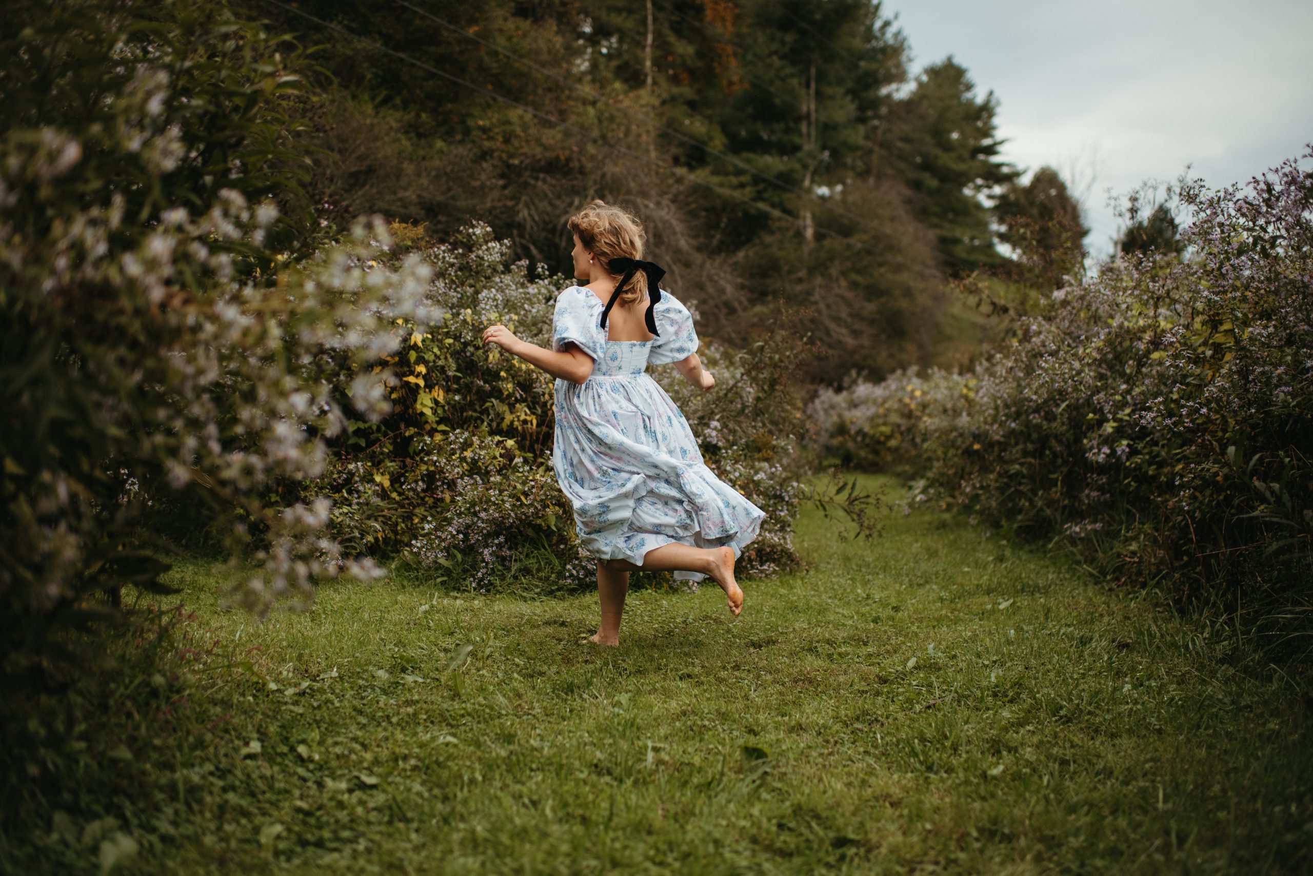 Woman in Selkie La Belle Etoile French Puff Dress running in field next to cottagecore barn