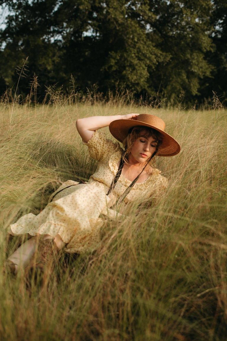 Woman in cottage core Christy Dawn dress with Behida Dolic bolero hat in a field